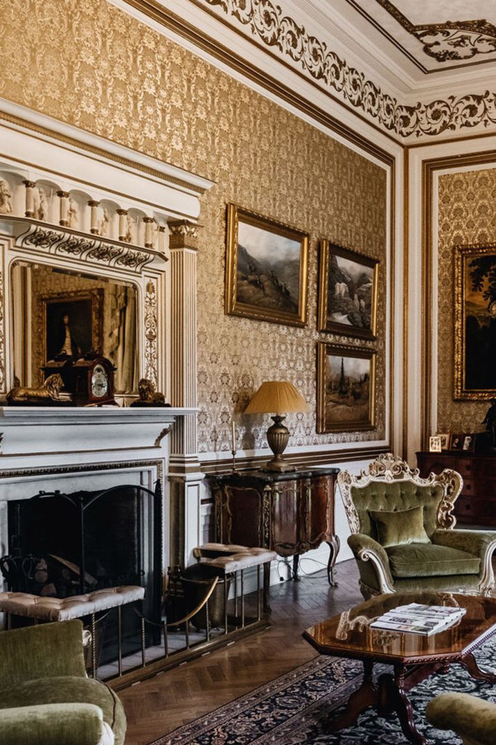 Traditional castle wedding venue with plush green velvet chairs, gold accents and classic paintings in the living room 