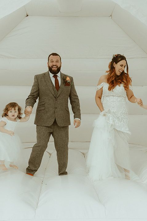 The bride and groom play on bouncy castle at the wedding with their children - Kids entertainment ideas