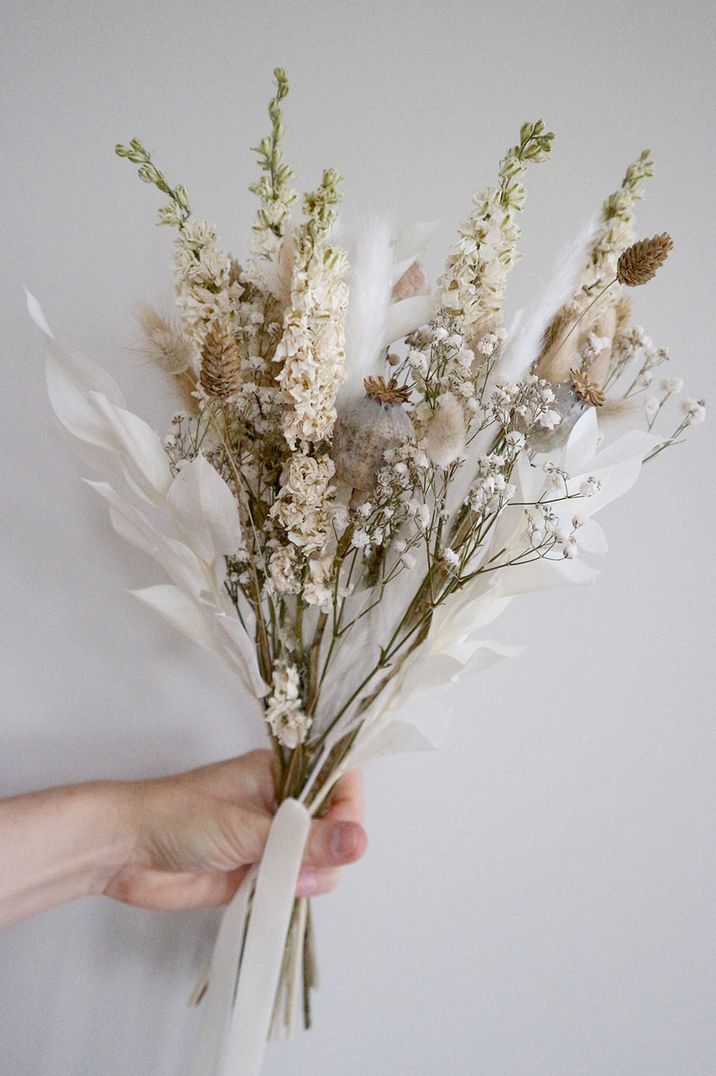 Hand holding muted dried flower bouquet