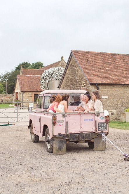 Open top pink Land Rover wedding car with tin can decorations 