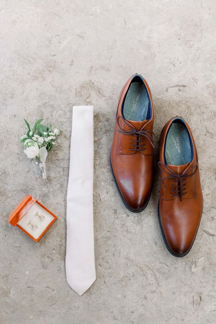 Brown brogues, white tie and neutral boutonnière 