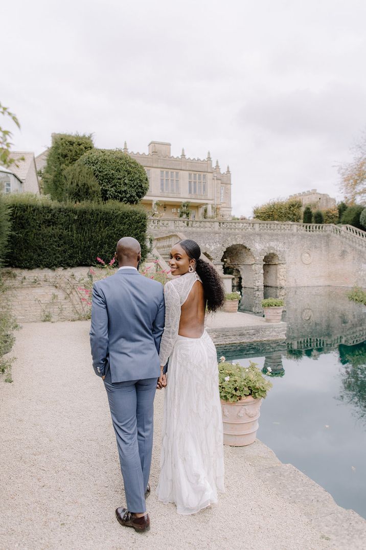 Groom in a blue suits walks with the bride in a backless wedding dress at Euridge Manor 