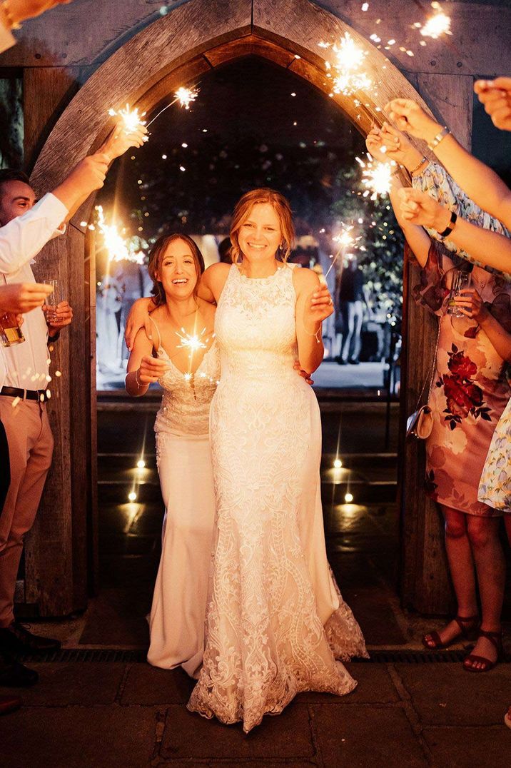 Brides in complimenting sleeveless lace wedding dresses doing sparkler exit - timeline of wedding day 