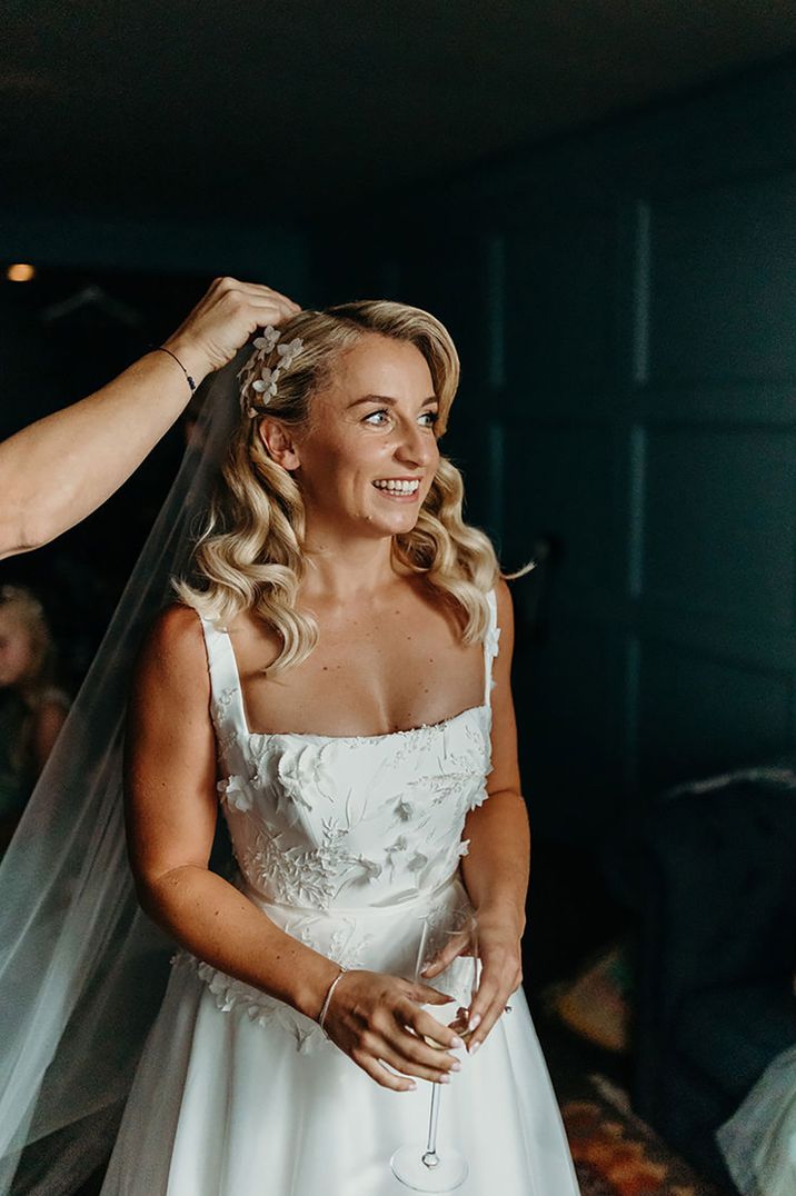 Bride with blonde hair in a side swept hairstyle with white flower hair accessory 