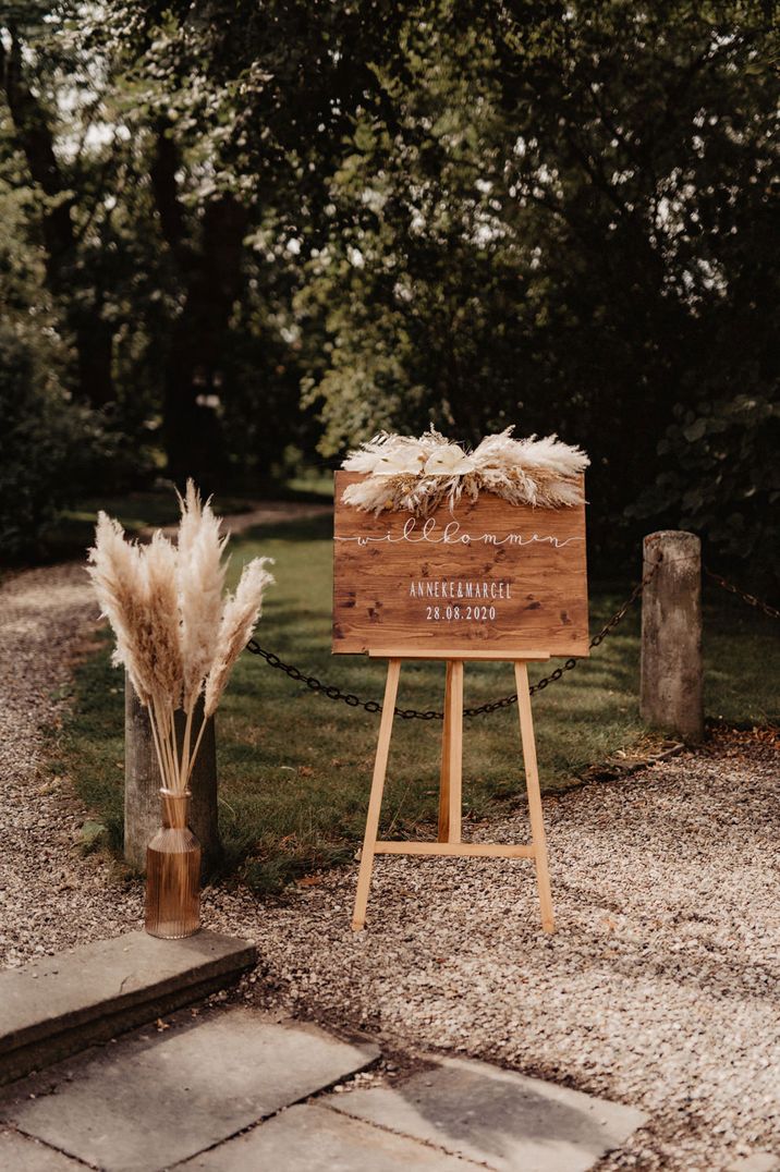 Wooden welcome sign rest on an easel with dried pampas grass decor 