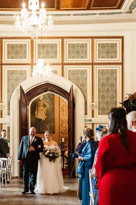 Bride in off shoulder tulle wedding dress walking down the aisle at Drumtochty Castle wedding venue Scotland with father of the bride 