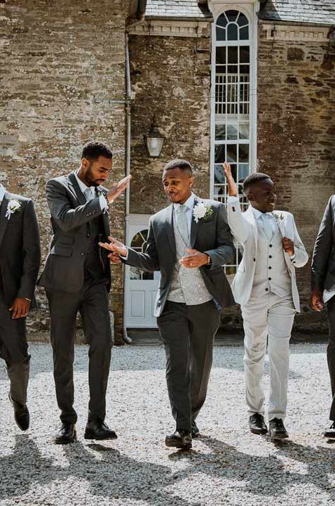 Groomsmen in matching deep grey wedding suits and light rose boutonnieres at Tredudwell Manor wedding venue - last minute wedding preparations