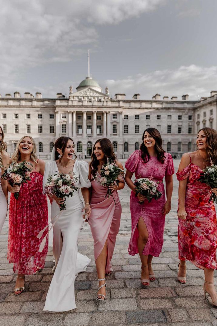 Bridesmaids in pink floral mismatched bridesmaid dresses walking with bride in short puff sleeve wedding dress at Somerset House wedding