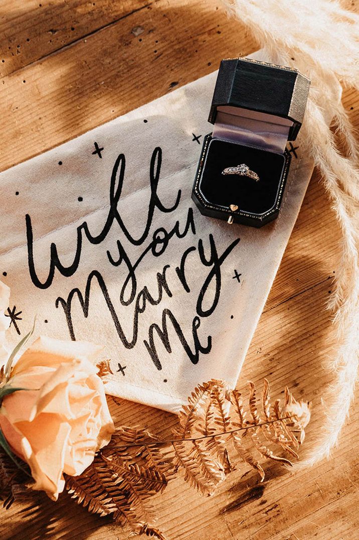 Black and white 'will you marry me?' wedding banner signage with ring box and engagement ring for Valentine's Day proposal ideas 