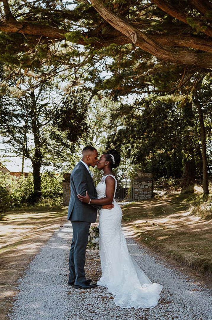 Groom wearing grey suit with bride in lace wedding gown 