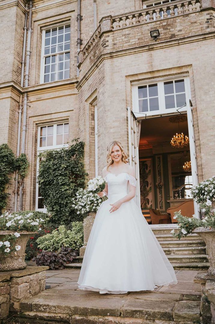 Bride in off shoulder lace detail wedding dress outside Hedsor House