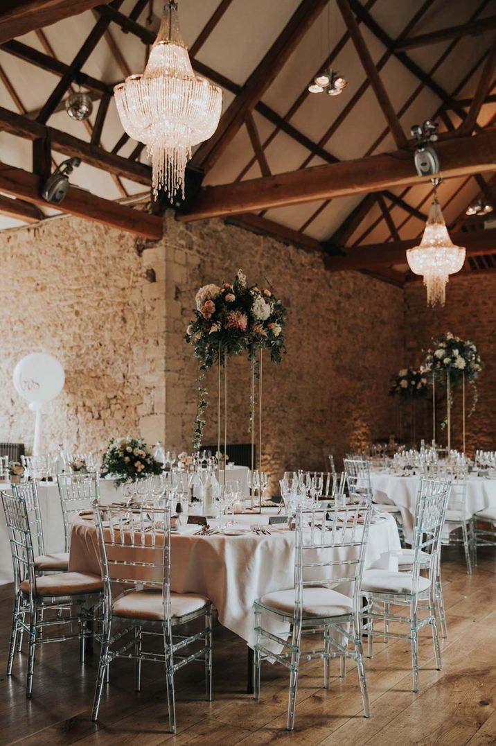 Reception room with neutral tones, fairy lights and large wooden beams with hanging floral decorations at Notley Abbey