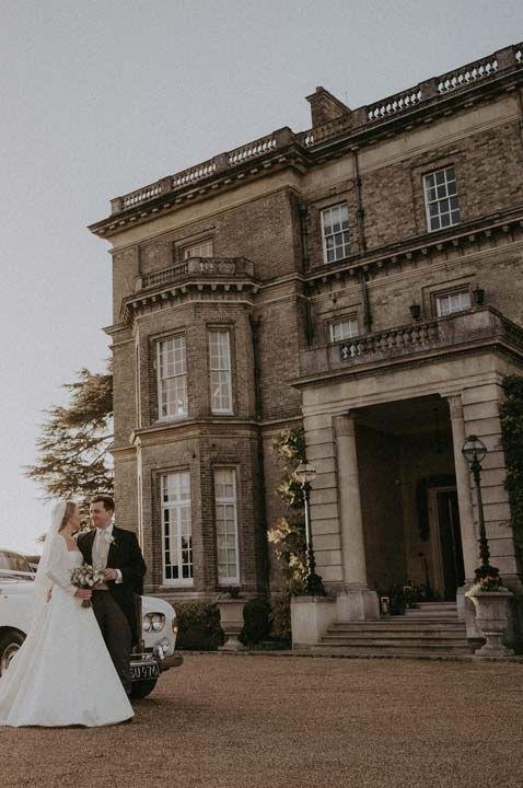 Bride and groom walking outside the exterior of Hedsor House country house wedding venue