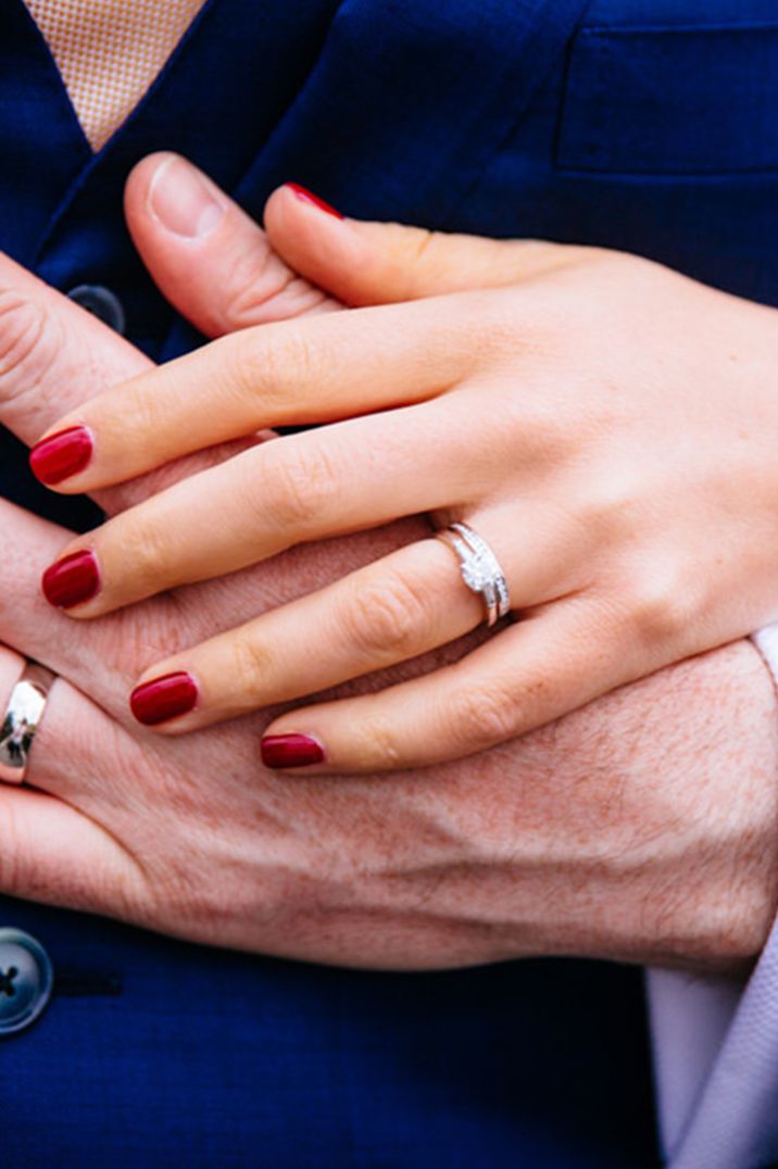 Bride has short red engagement nails with round brilliant diamond ring 