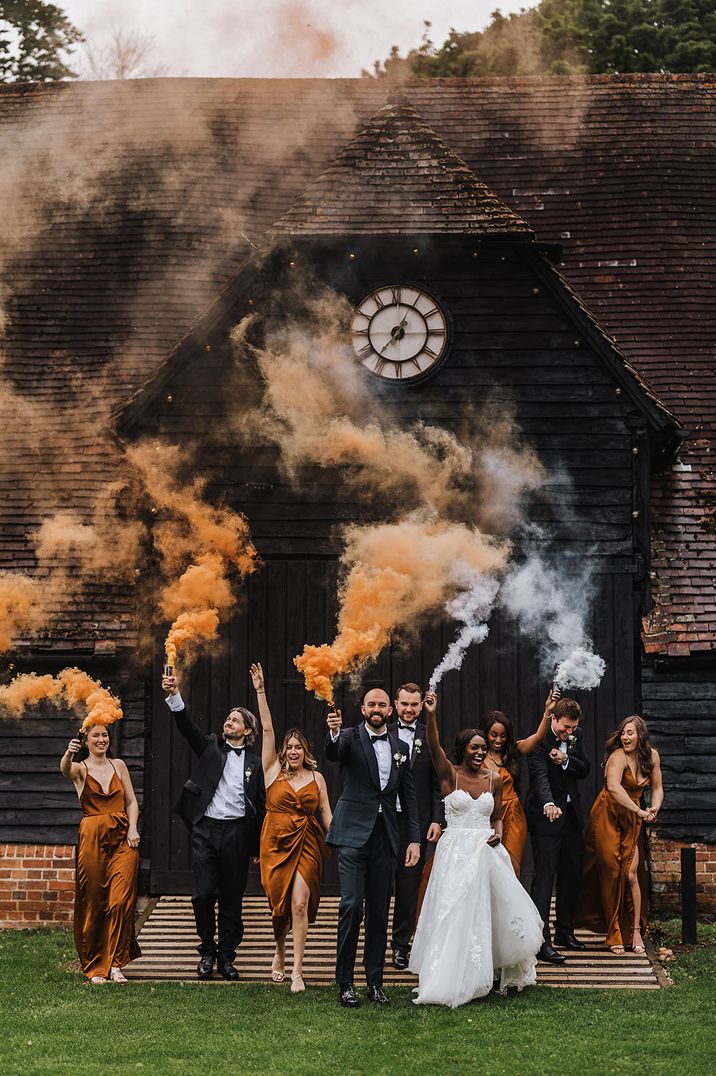 Orange and white smoke bomb wedding photo with bridesmaids in orange satin gowns 