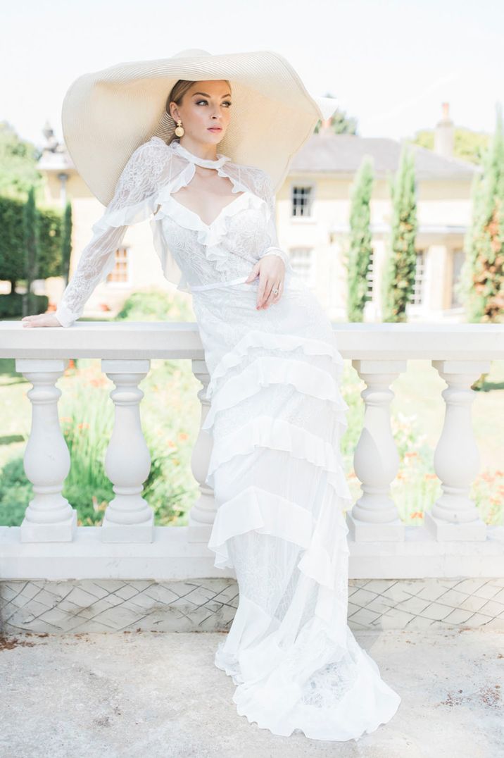 Bride wears floppy sunhat with high neck lace wedding dress 