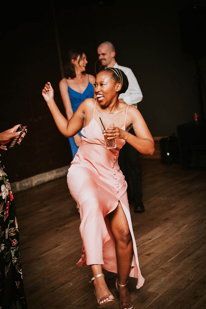 The black bride in a pink satin reception dress with leg split and gold crown 