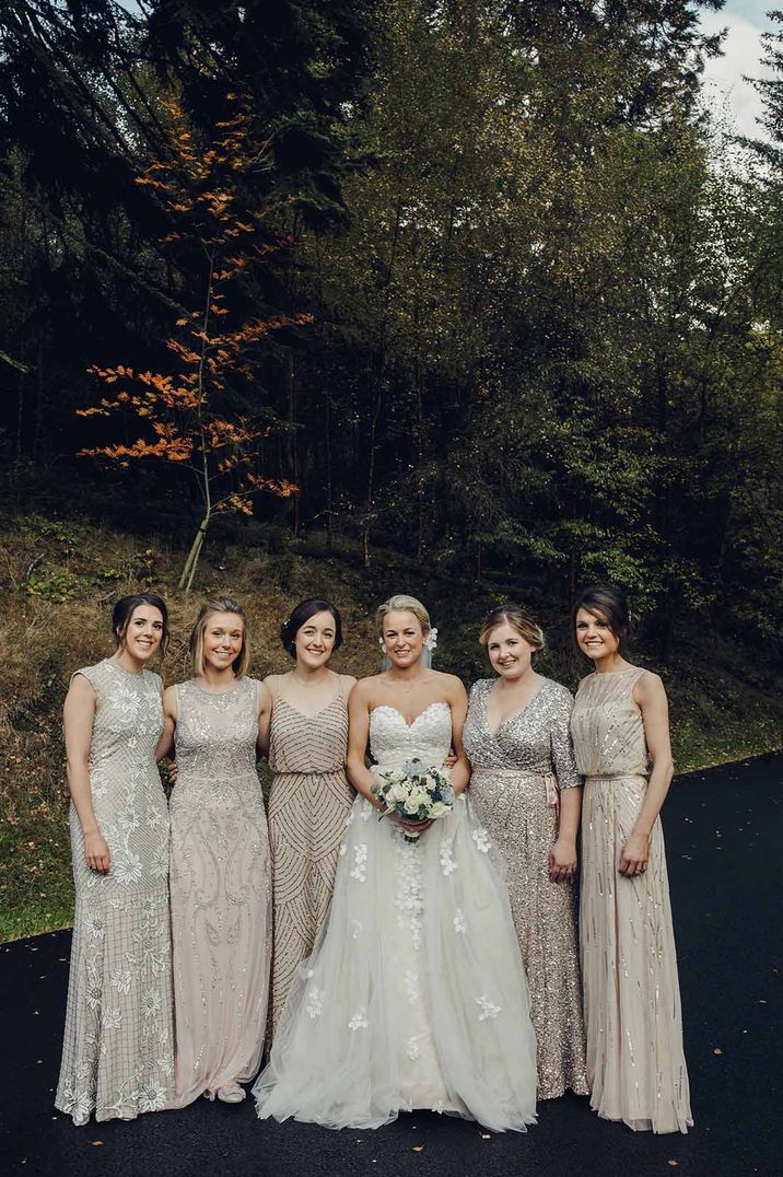 Bride in sweetheart neckline strapless wedding dress standing with bridal party in mismatched embellished bridesmaid dresses