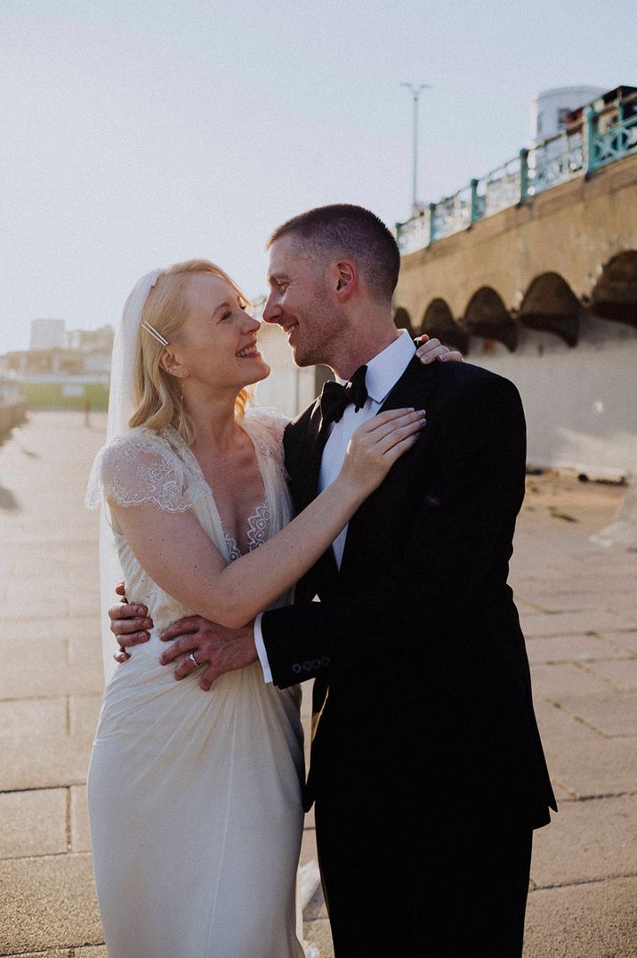 Bride and groom pose for golden hour wedding photos at Brighton Pier 