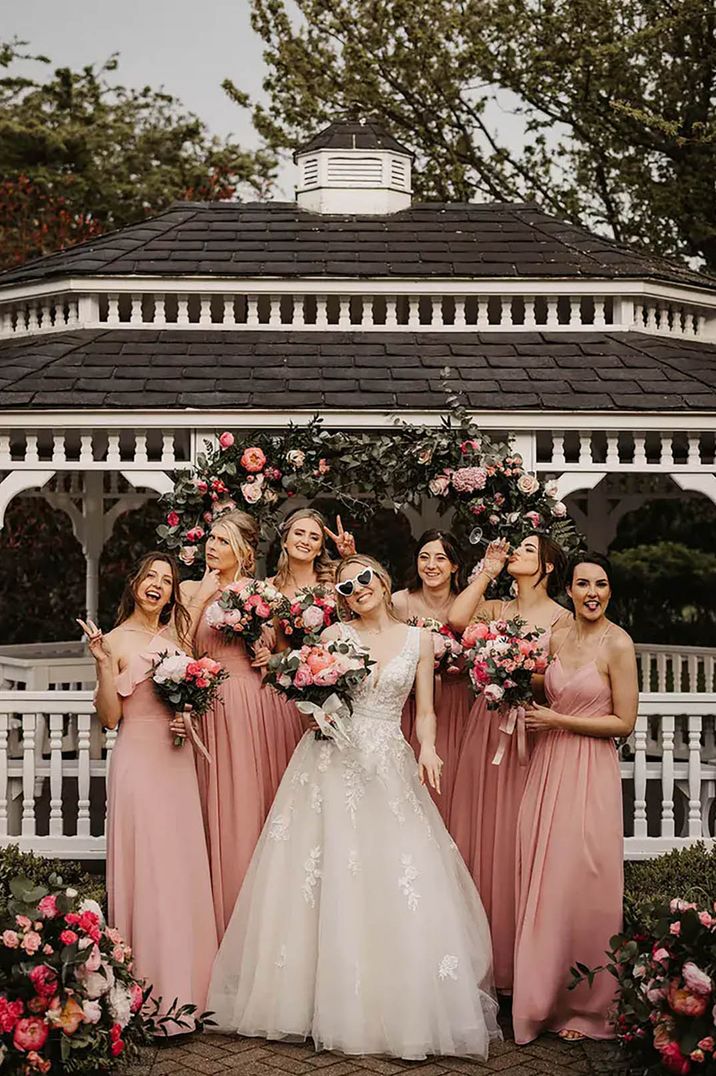 Bride posing with her bridesmaids wearing pink spring bridesmaid dresses