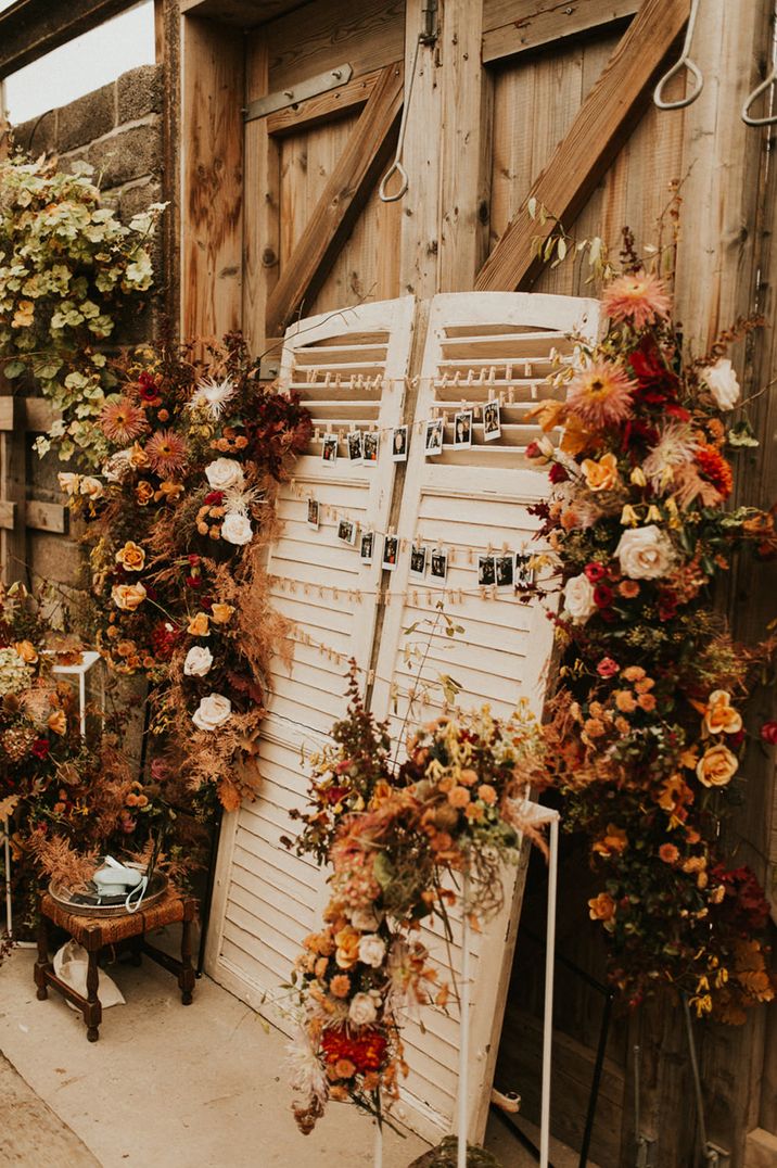 Shutter wedding decor with hanging polaroid pictures on decorated in autumn leaves and flowers 