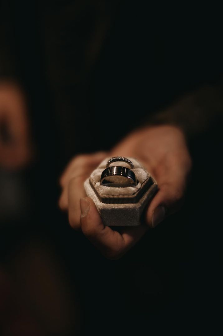 A man presents a velvet ring box with his and hers wedding bands 