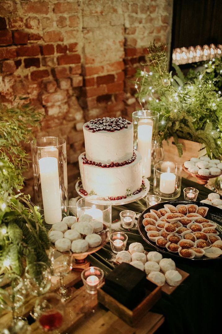 Christmas winter wedding dessert table with white wedding cake topped with red berries with frosted mince pies 