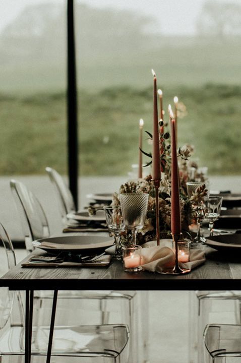 Retro modern wedding tablescape with clear chairs and orange candles