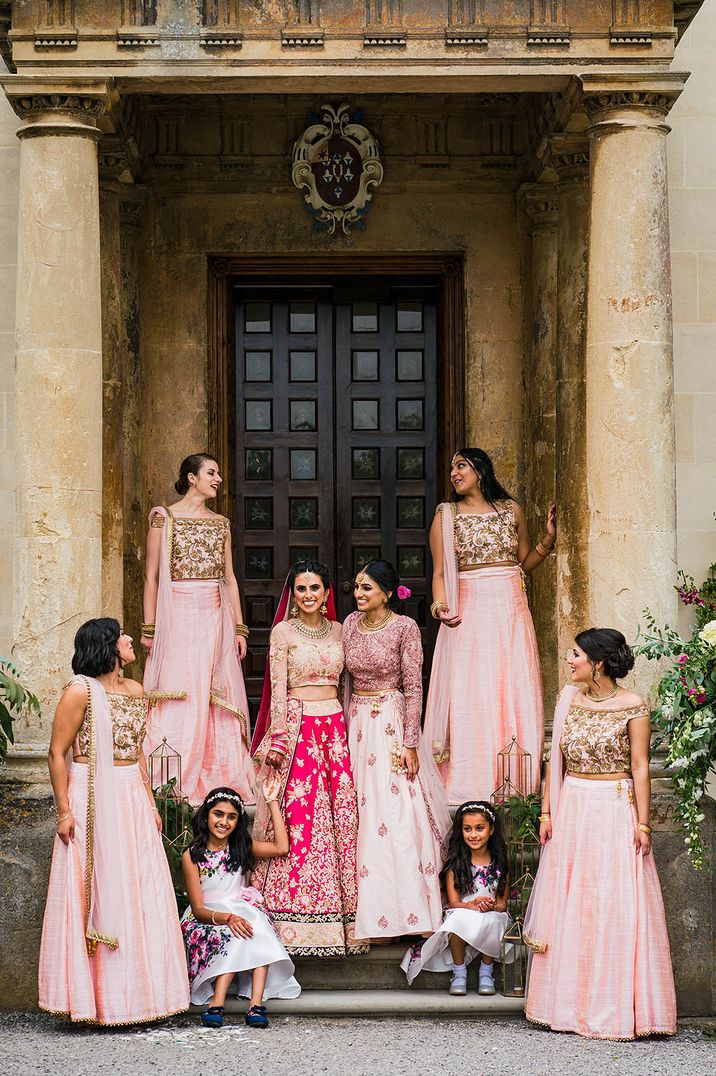 Bridal party standing at entrance to Elmore Court with the bridesmaids in pink and gold outfits for Hindu fusion wedding 