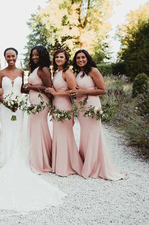 Bride in sleeveless structured wedding dress with puddle train standing with bridesmaids in halterneck pink bridesmaid dresses 