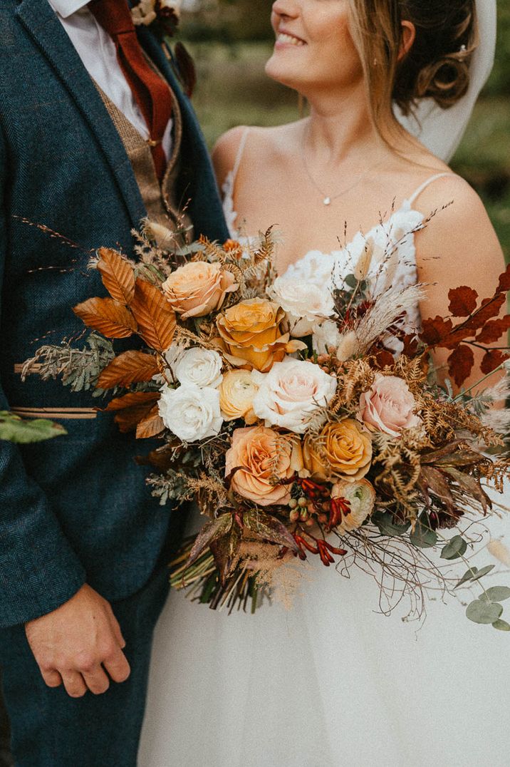 White, orange and pink rose wedding bouquet with autumnal leaves 