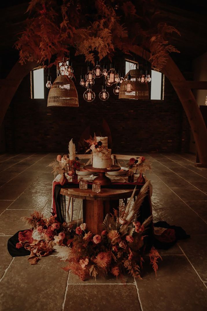 Moody and ambient sweetheart wedding dessert table with pampas grass and pink flowers with rustic wedding cake 