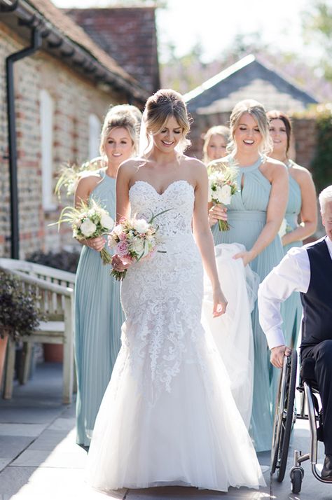 A bride walks alongside her dad who is in a wheelchair at an accessible wedding venue. 