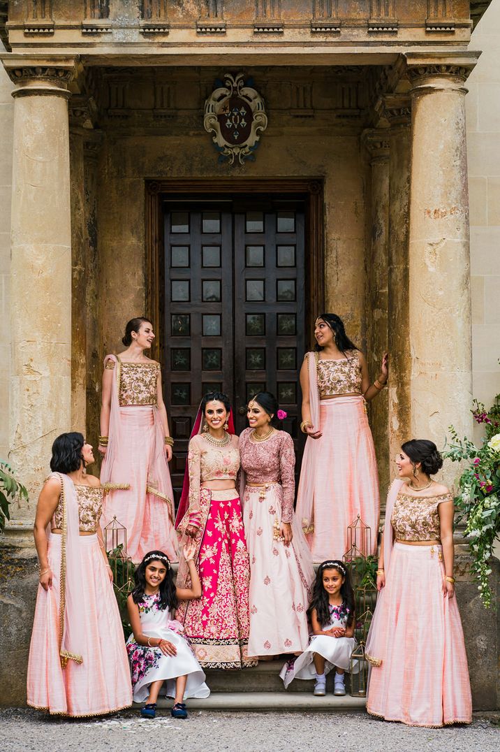 Bridesmaids in pink traditional Asian wedding attire standing on the steps at Elmore Court wedding venue 