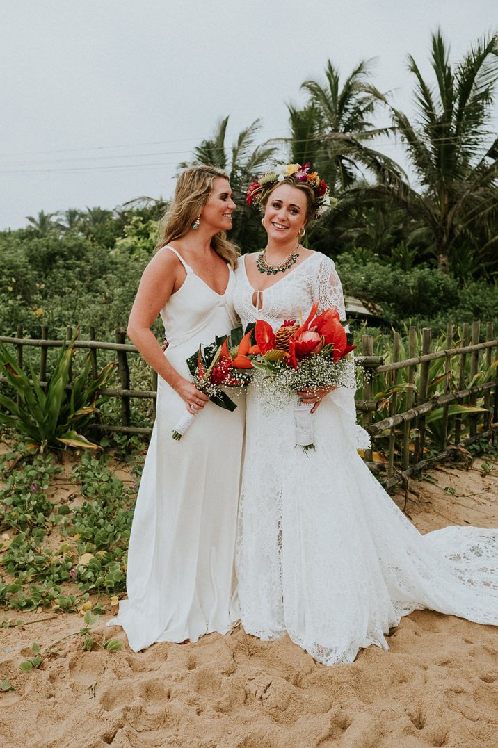 Bride and best woman in white dresses holding red bouquets