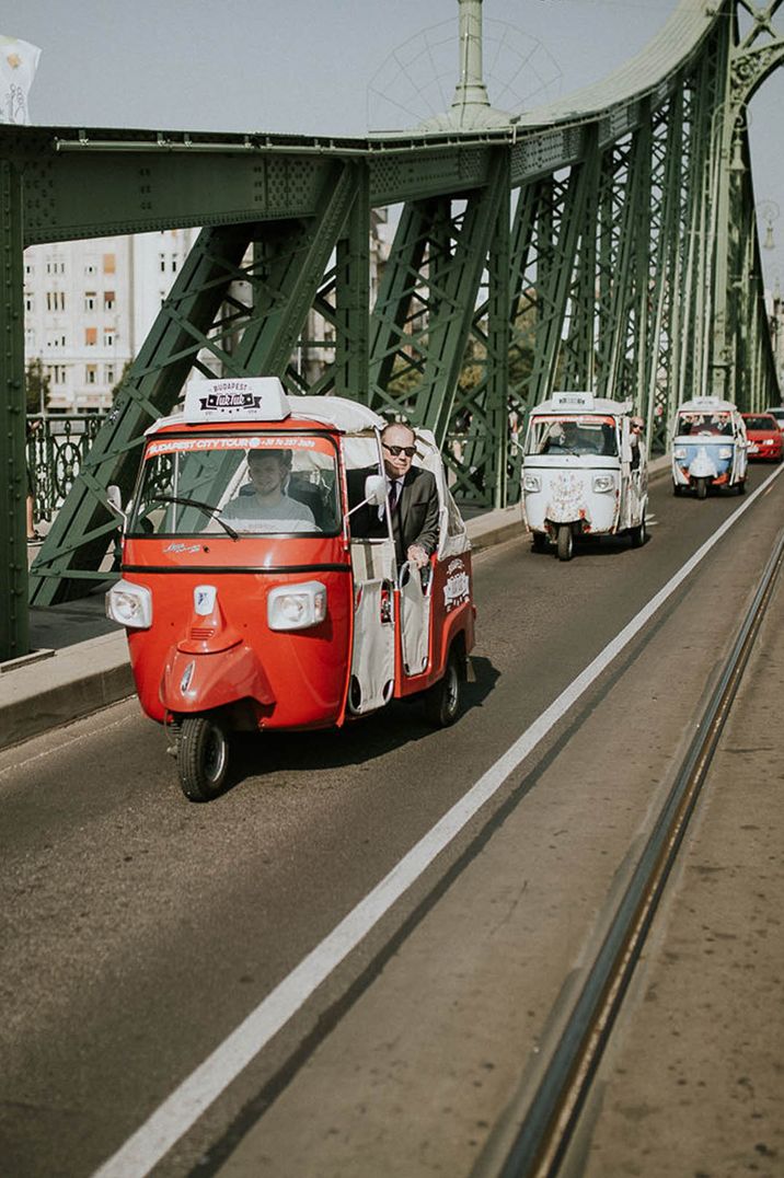 Couple at Budapest wedding in red and white Tuk Tuk wedding transport