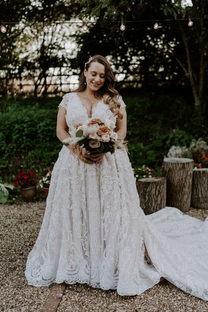 Homemade lace wedding dress with deep v neck and neutral toned bouquet