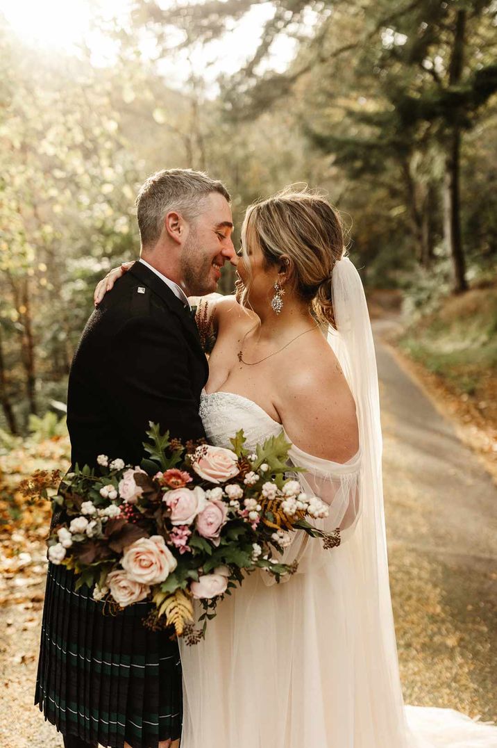 Newlyweds at Drumtochty Castle wedding leaning in for a kiss as they stand outside together on sunny autumn day