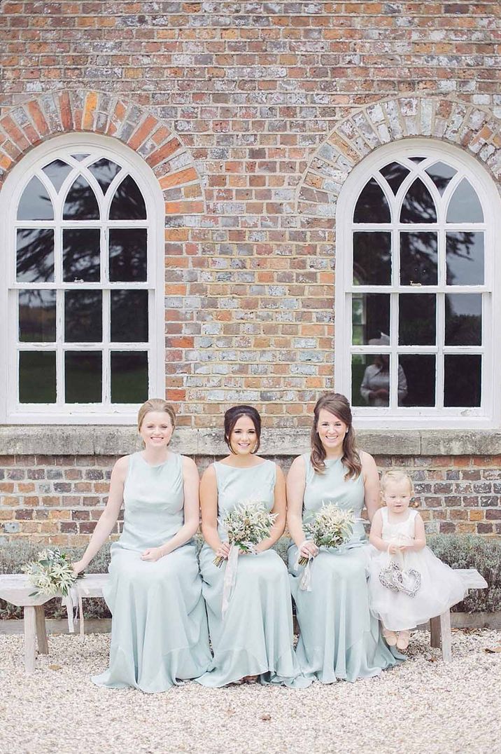 Bridesmaids in baby blue satin bridesmaid dresses with pink ribbons at Wasing Park