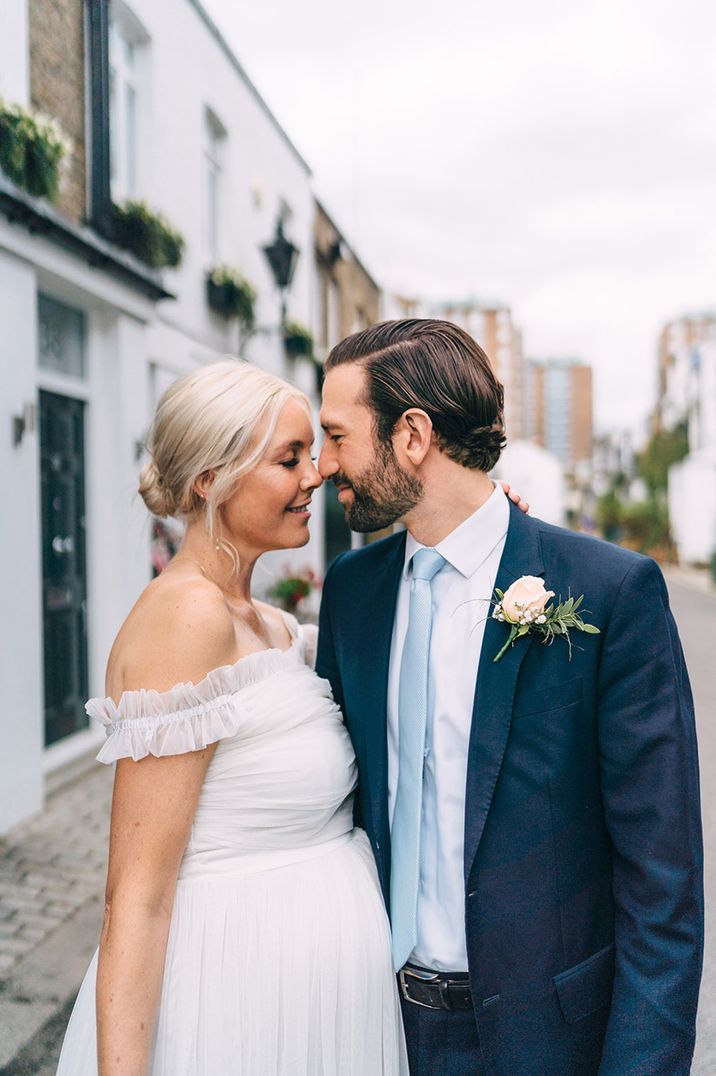 The bride and groom share a kiss on their wedding day with the bride wearing a floaty maternity wedding dress 