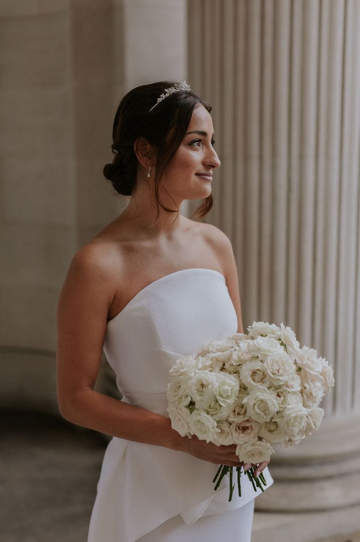 Bride in strapless wedding dress carrying white rose wedding bouquet 