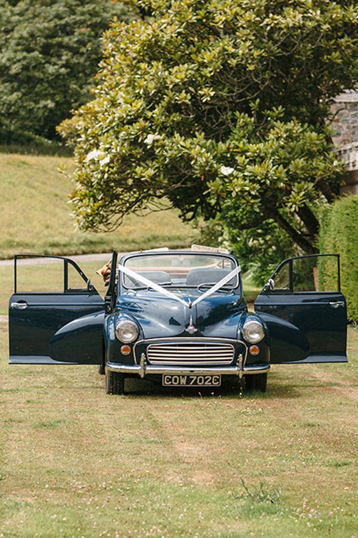 Vintage dark blue wedding car decorated with white ribbon 