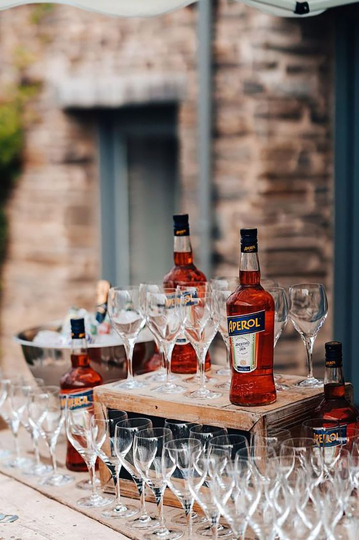 Aperol spritz drinks station with bottles of Aperol and empty glasses by James Fear Photography