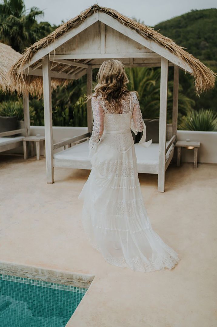 Ibiza wedding with bride wearing a white maxi dress outdoors by a pool and sun loungers by Balti Rėmeliai