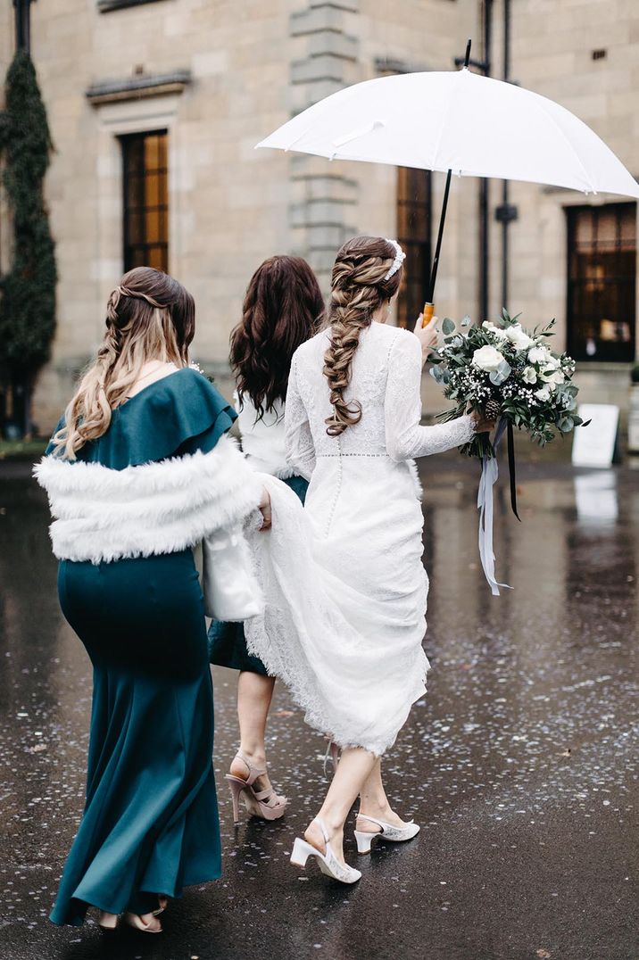 Bride with braided hairstyle in long sleeve lace wedding dress walking with bridesmaids in green dresses