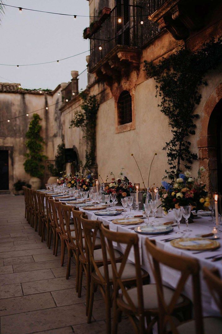 Rustic outdoor wedding tablescape with fairy lights suspended and dried flower centrepieces 