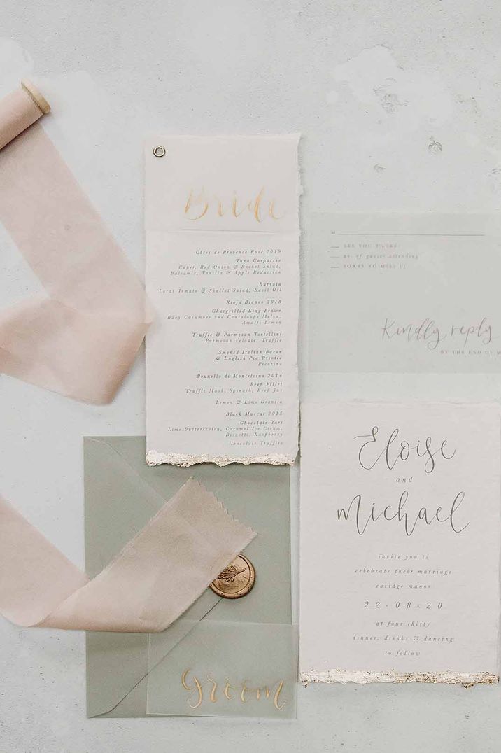 Sage green and baby pink pastel wedding stationery with menu and invitation next to the sage green envelop with gold wax seal 