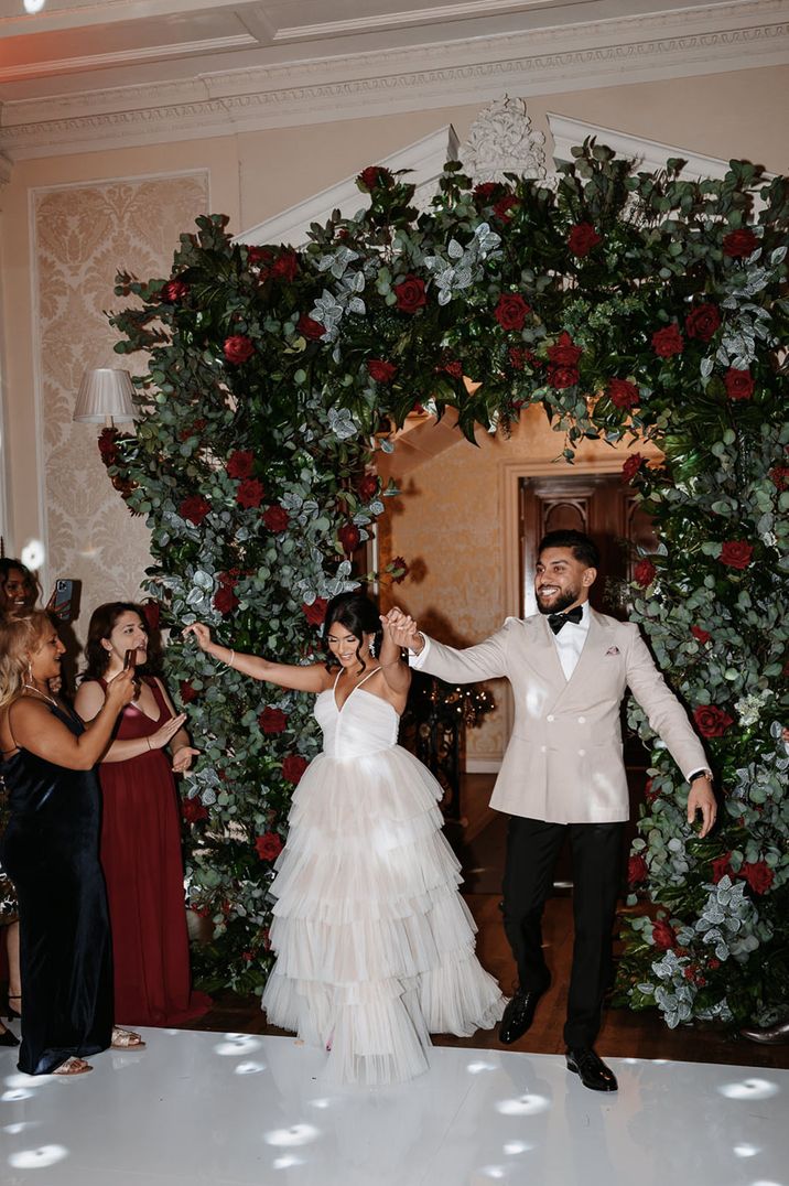 Large red rose flower arch decorating the entrance to the wedding reception at winter wedding 