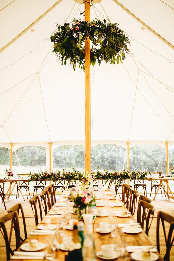 Wonwood Barton wedding venue with wooden tables decorated with colourful flower arrangements decorating the marquee 