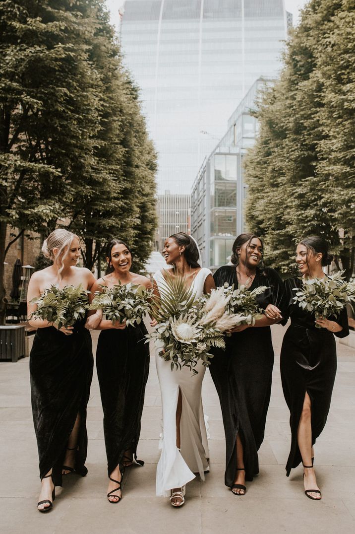 Bride surrounded by bridesmaids in black satin dresses with bouquets